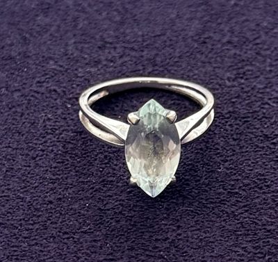 a close up of a ring with a green stone on a purple surface