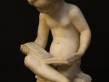 a statue of a boy sitting on a rock reading a book