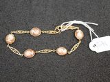 a close up of a gold chain bracelet with pearls on it