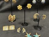a group of earrings and brooches on display on a black background