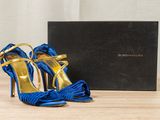 the blue and gold high heeled shoes are next to a black box