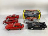 trois petites voitures rouges et noires et une boîte de petites voitures noires et rouges