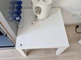 une table blanche sur laquelle se trouve une tasse, près d'une porte