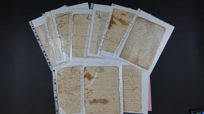 beaucoup de vieux papiers posés sur une table, à côté d'un téléphone portable