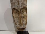 an image of a wooden sculpture of a face on a black stand