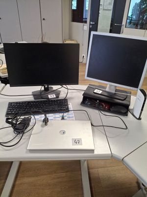 un bureau sur lequel se trouvent un ordinateur portable, un écran et une imprimante
