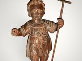 an old statue of a boy holding a cross and a stick
