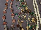 many different necklaces and bracelets laid out on a table
