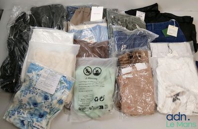 de nombreux vêtements de toutes sortes, rangés dans des sacs posés sur la table