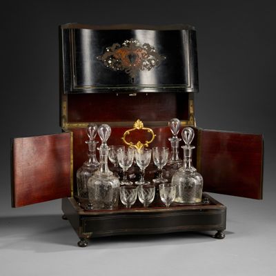bottles and glasses in a wooden case with a clock on top