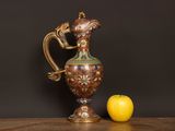 a gold vase and an apple on a wooden table