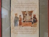 painting of a group of people sitting around a table with a vase on it