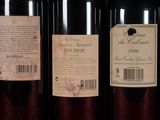 three bottles of red wine are lined up on a shelf