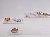 three pieces of jewelry on display on a white surface