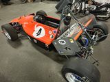 an orange race car that is parked in a garage