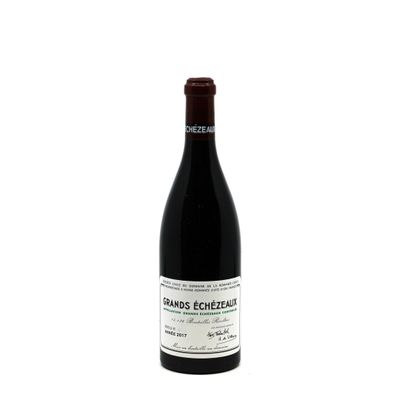 the bottle of red wine is sitting on a white surface