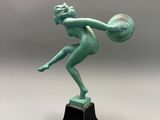 une statue représentant une femme tenant une boule, posée sur un socle noir