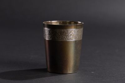 une image représentant une tasse en métal posée sur une surface noire