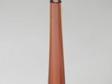 a tall orange vase sitting on a table in a room