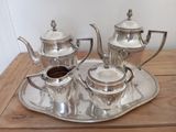 a silver tea set sitting on a tray on a table