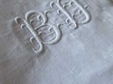 a close up of a white pillow with a monogram on it