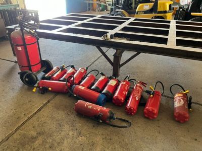 several fire extinguisors are lined up on a table in a warehouse