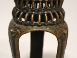 an image of a small bronze candle holder with a candle on top of it