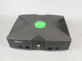 a close up of a black xbox game console with a green button