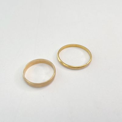 deux alliances en or sur une surface blanche