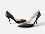 une paire de chaussures noires à talons hauts sur une surface blanche