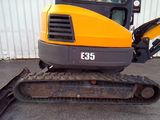 a yellow and black excavator parked in front of a building