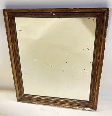 an old mirror is sitting on a white surface next to a white wall