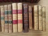 many old books lined up on a wooden shelf