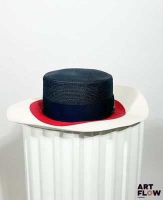une poubelle blanche surmontée d'un chapeau rouge et bleu