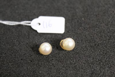 a pair of pearl earrings on a black surface with a price tag