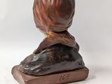 bronze sculpture of a woman sitting on a rock with her hands on her head