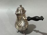 an antique silver teapot with a black handle on a white surface