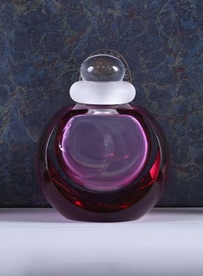 a purple glass bottle with a white top on a table