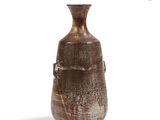 un vase brun posé sur une surface blanche