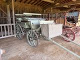 une calèche dans une grange, avec une autre calèche en arrière-plan