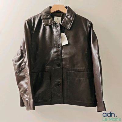 une veste en cuir suspendue à un cintre, avec une étiquette dessus