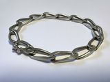 gros plan d'un bracelet métallique sur une surface blanche