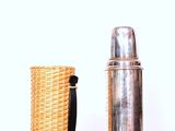 a silver bottle and a wicker basket next to each other
