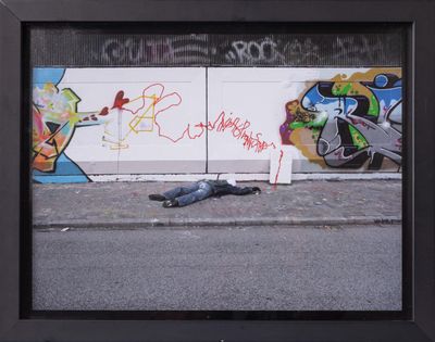 a picture of a man laying on the ground in front of a wall with graffiti