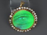 a close up of a green pendant with diamonds on a clear surface