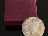 une vieille pièce d'argent posée à côté d'une boîte rouge sur une surface noire