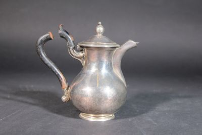 a silver tea pot with a handle on a table