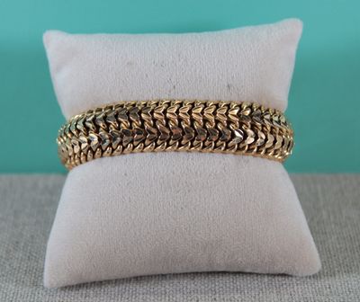 gros plan d'un bracelet en chaîne en or sur un oreiller