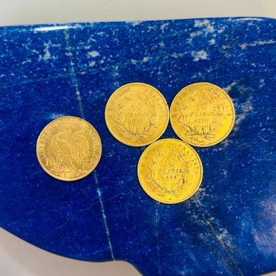 quatre pièces d'or posées sur une assiette bleue, sur une table
