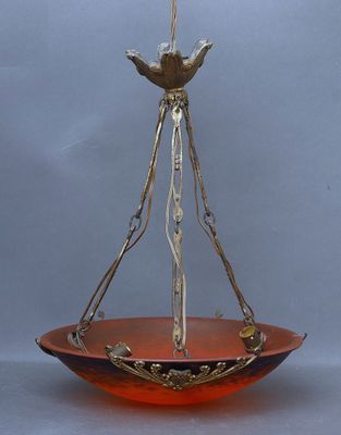 un bol en verre orange auquel est suspendu un oiseau au fond